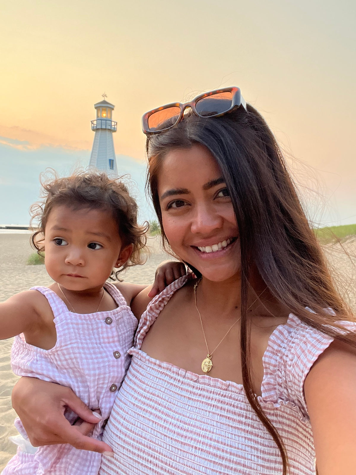 Euneece, founder of Immaculate Blessed, with her daughter at the beach, wearing her gold medal