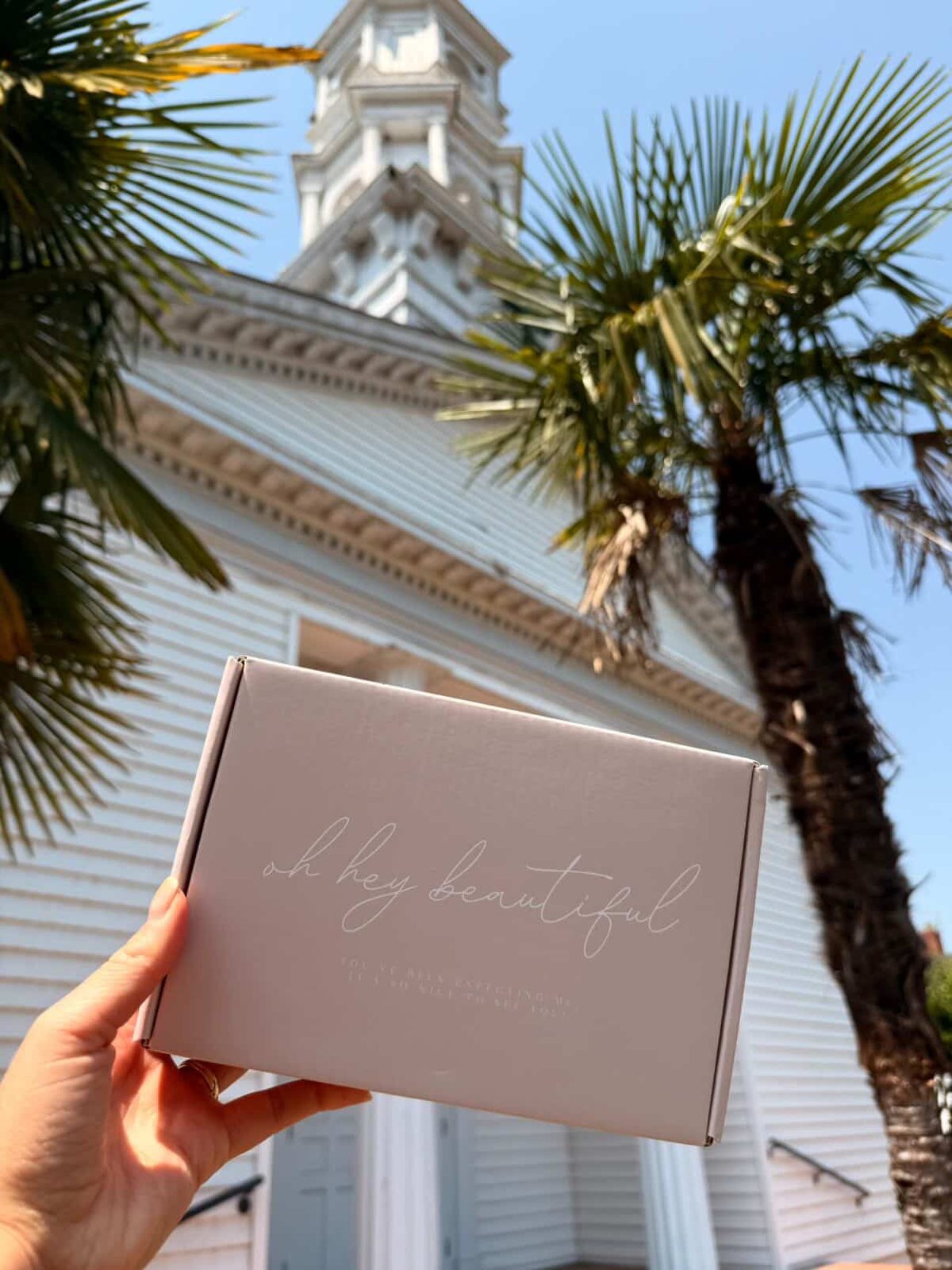 Immaculate Blessed gift box held in front of a church